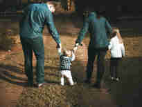 A family of four holding hands walking through a woods. Criminal Injuries Compensation Authority (CICA) claims solicitors