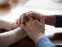 A couple holding hands rested on a table. Fatal accident claims and inquests solicitors