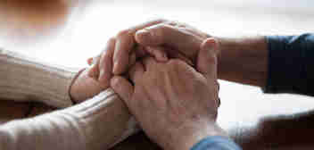 A couple holding hands rested on a table. Fatal accident claims and inquests solicitors