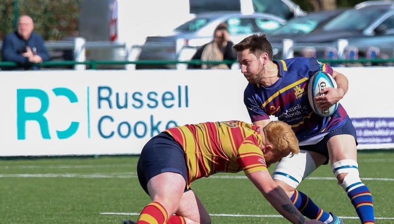 Action shot of wo opposing players from a Cobham RFC match Russell-Cooke sponsored banner in the background